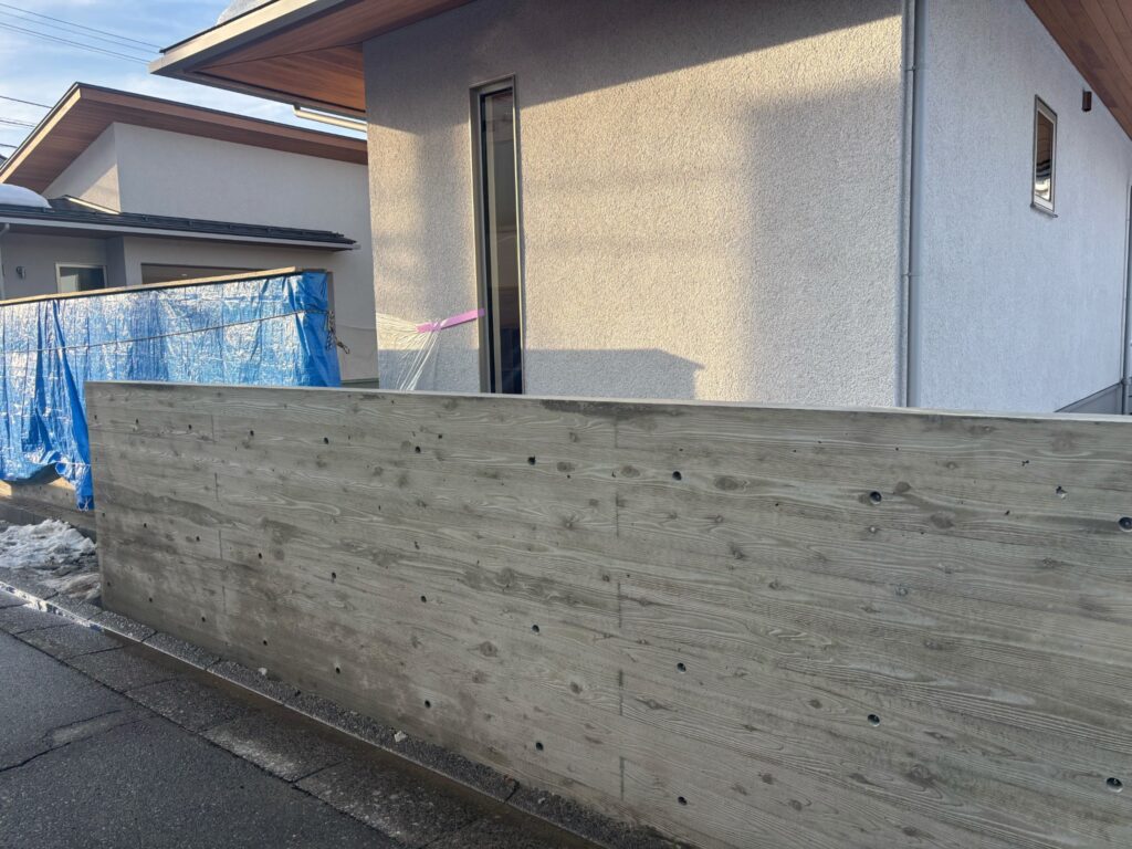 福井市T様邸の杉板擁壁型枠工事・道路側から見た木目仕上げの長いコンクリート壁